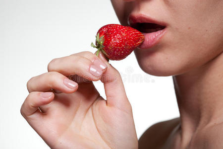 一个年轻女人咬着白色隔离的草莓