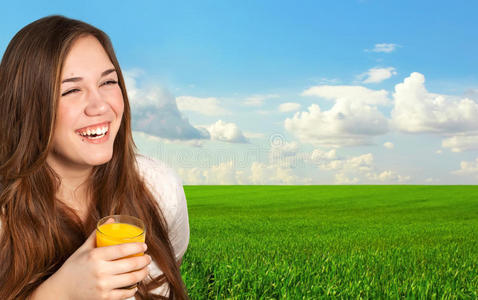 美丽的女孩拿着一杯果汁在田野的背景上微笑