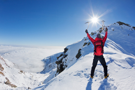 登山运动员到达顶部的雪山在阳光明媚的冬天