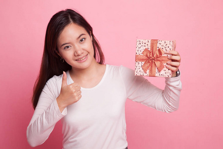 年轻的亚洲女人竖起大拇指与一个礼品盒