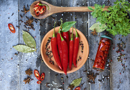 新鲜的红辣椒在碗里与香料和勺子在木制的背景, 顶部视图