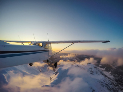小飞机飞行上层建筑美丽的加拿大山风景在一个充满活力的日落期间。拍摄于加拿大不列颠哥伦比亚省温哥华以北