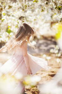 美丽的金发女孩在盛开的樱桃园里