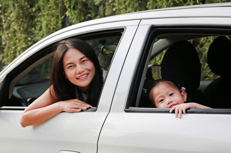 快乐的年轻女子和她的小女孩坐在车里