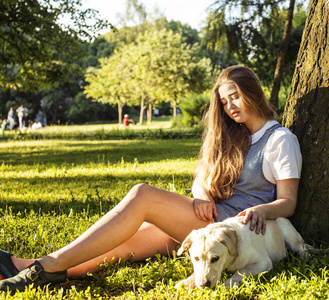 年轻有魅力的金发碧眼女人玩她的小狗绿色公园