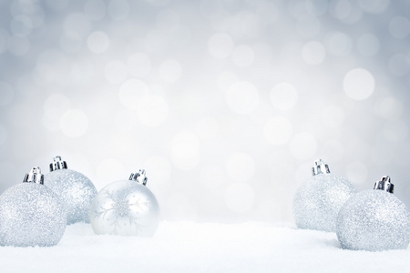 雪与银色的背景上的银色圣诞小玩意