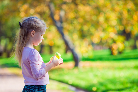 可爱的小女孩，与苹果公司在美丽的花园，在秋季的一天