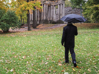 公园里有黑色雨伞的男人