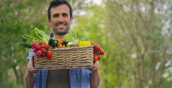 一个快乐的年轻农民，一篮子里拿着新鲜蔬菜的画像。大自然的生物 生物产品 生物生态学，增长了自己的双手，素食主义者，沙拉健康概