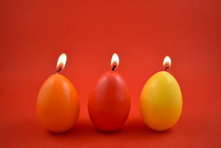 鸡蛋蜡烛股票图像。红色背景上的彩色蜡烛。五颜六色的复活节蜡烛。复活节概念