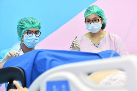 亚洲男性产科医生和护士被送到病人躺在医院产房的床上。