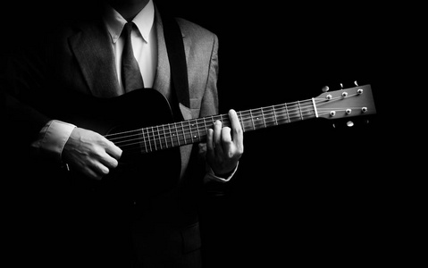在玩吉他，黑色和白色的西装男音乐家