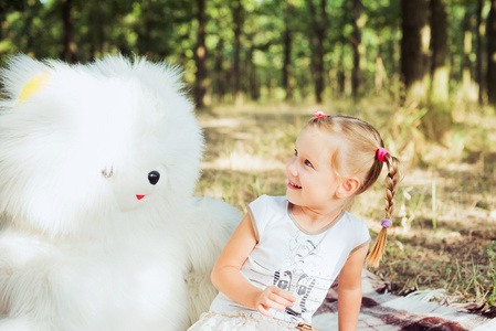 小玩大白熊玩具在公园里的漂亮女孩