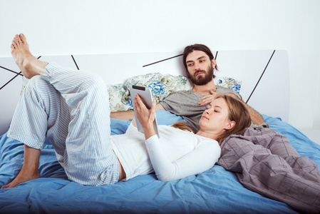在床上使用平板电脑的年轻白人夫妇