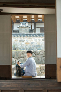 一个年轻男子在韩国传统的房子里做背包旅行