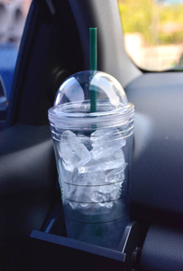 在玻璃汽车持有者清楚地摇摆冷的杯子。杯子里装满了冰和水