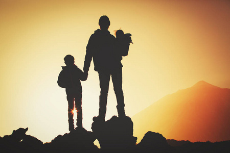 父亲的剪影与孩子远足在日落山图片