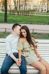 幸福的年轻夫妇在爱坐在公园长椅上拥抱