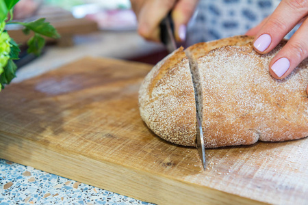 女人切新鲜自制面包在木板上