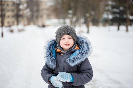 可爱的小滑稽的孩子在五颜六色的冬天衣裳有乐趣与雪, 室外在雪期间。户外活动, 冬季有孩子。戴着保暖帽手手套和围巾的孩子