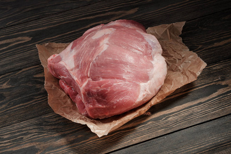 一块生猪肉的肩膀。深色背景纸上的猪肉里脊肉