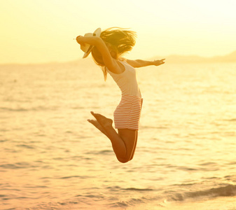 美丽幸福的女人，白天阳光灿烂的夏天在海滩上跳跃