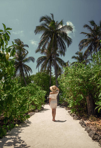 在棕榈树下穿白裙子的女孩。马尔代夫。度假。娱乐。热带地区