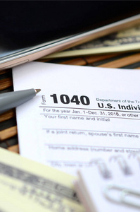 钢笔, 笔记本, 智能手机和美元是在税收形式1040美国个人所得税申报表。纳税时间