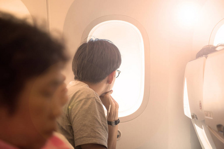 亚洲人戴眼镜在飞机上的望出窗外