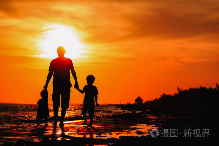父亲和两个孩子走在日落时分
