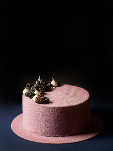 美味的慕斯蛋糕覆盖粉红色天鹅绒和装饰与巧克力球在黑暗的背景下