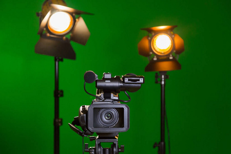 一个摄像机和一个聚光灯与绿色背景上的菲涅耳透镜。在室内拍摄。色度键