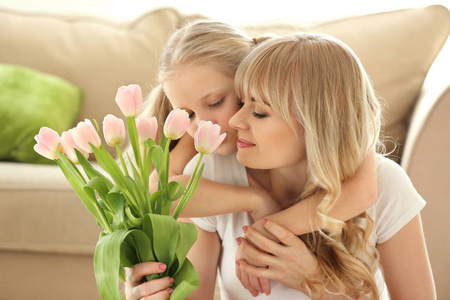 可爱的小女孩和她的母亲的肖像在家里的郁金香花束