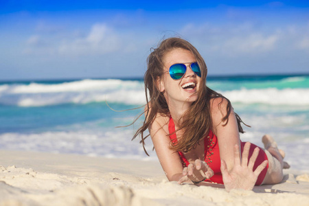 长头发的女人，在红色比基尼和太阳镜躺在热带海滩上的画像。拉拉迪戈 塞舌尔