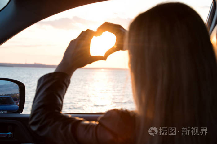 照片 一名年轻女子向车窗外看在 sea.heart 人手所造的日落.jpg