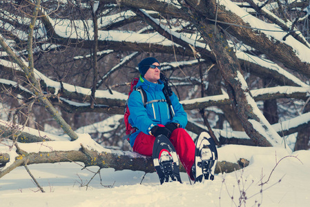 穿雪鞋的快乐徒步旅行者坐在树上