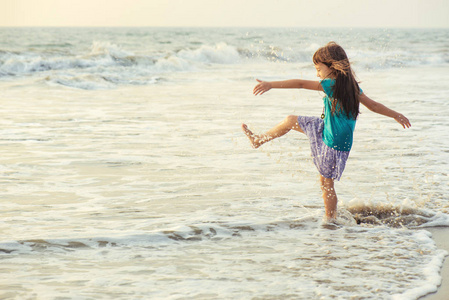 小的亚洲女孩玩和日落时分在海上玩乐