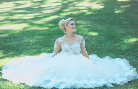 幸福可爱的新娘，在白色的婚纱礼服在绿色的草地上