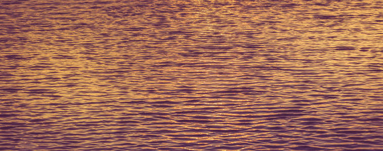 美丽的橙色和紫色的日落光的海波纹