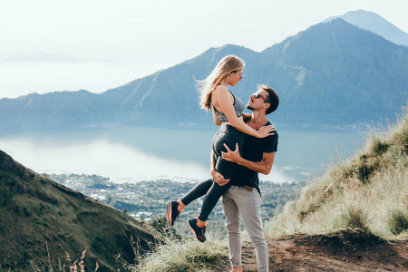 情侣坐在悬崖上的男人和女人轻松的山和云鸟瞰爱情和旅行的快乐情绪生活方式的概念。年轻家庭旅行活跃冒险假期, 时髦