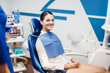 女孩患者坐在牙医的椅子上笑