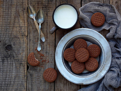 白色奶油和杯牛奶木背景上的巧克力饼干。选择性的焦点