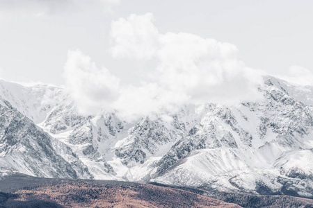 云层下覆盖着积雪的山峰山脉。山谷和悬崖景观