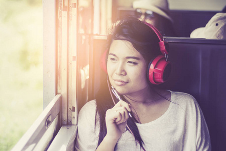 亚洲女人坐在一列火车同时 t 在听音乐