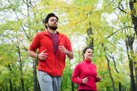 在秋天的公园，夫妇一起慢跑跑步的年轻白人夫妇