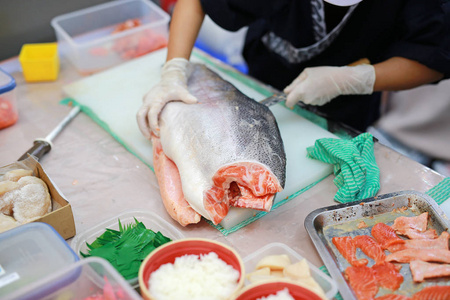 厨师在切板上切鲑鱼。海鲜菜配料