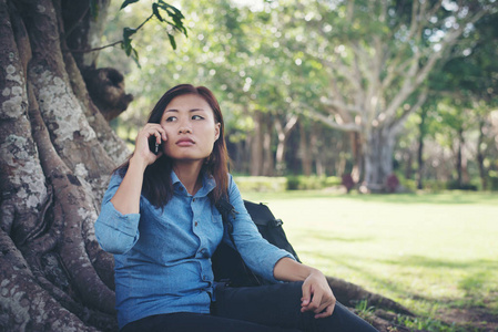 年轻的时髦女人坐在她的电话, 而在绿色