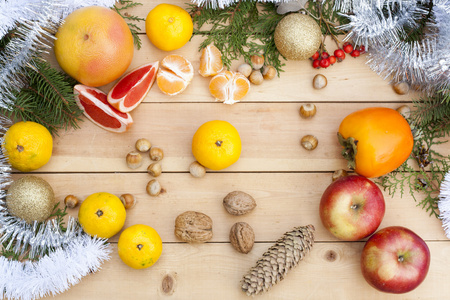 在圣诞节装饰圣诞树 坚果和轻木背景上的苹果橘子