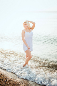 年轻美丽的白种人女性在日出或日落海滩上晒太阳