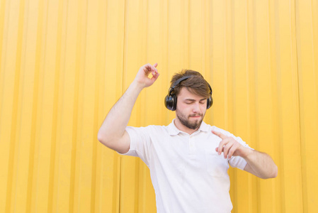 一个快乐的人听音乐的耳机和微笑的背景下, 黄色的墙壁。从音乐补丁。快乐音乐爱好者听音乐